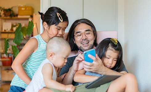 Dad on the phone with 3 kids in his lap