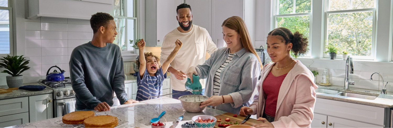 Woman using electric mixer in the kitchen surrounded by family