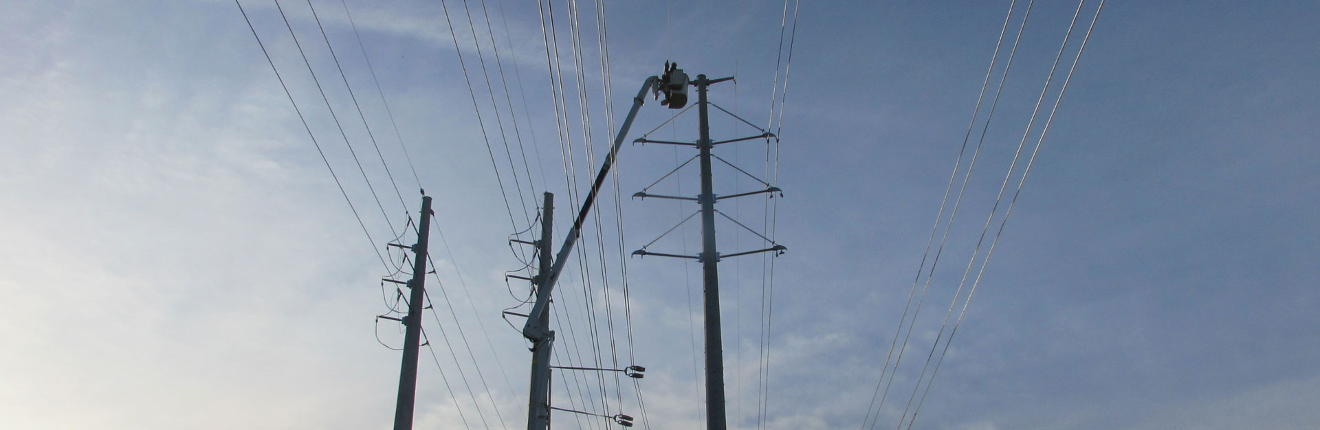 Lineman working at top of bucket truck extended arm on power lines