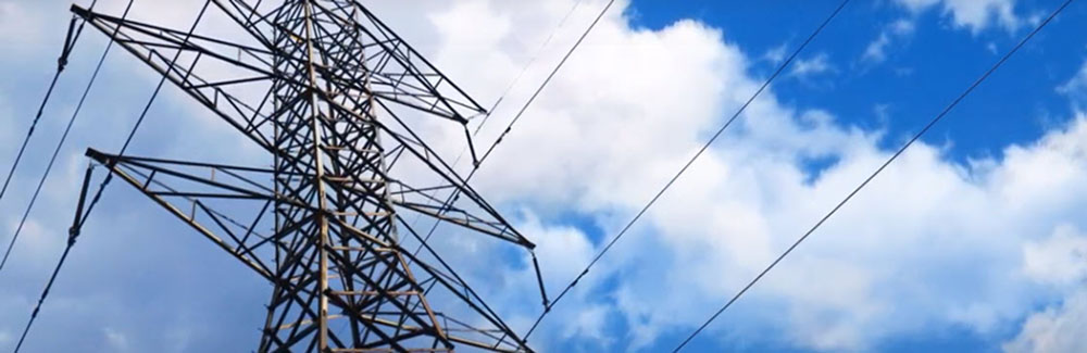 Powerlines against a blue sky with white, fluffy clouds