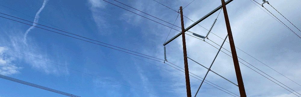 An h-frame power line pole against a blue sky