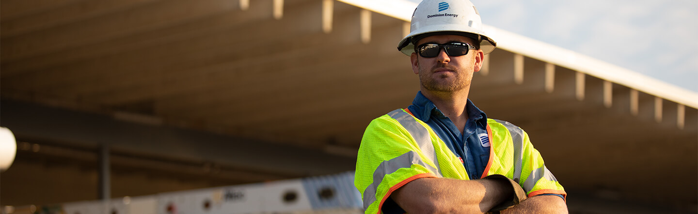 Dominion Energy Employee Standing in Front of Service Trucks