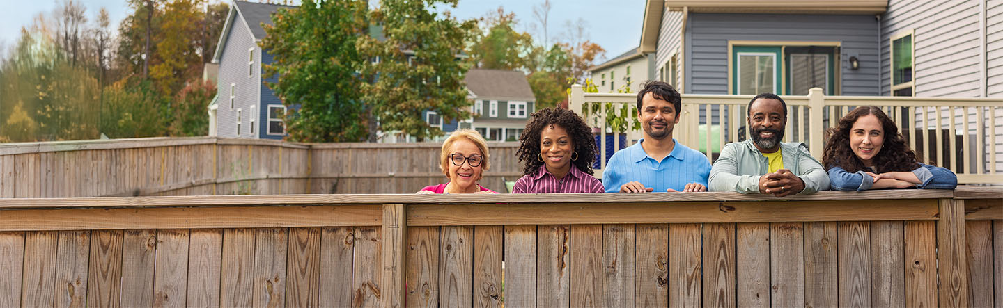 Neighbors smile across a fence