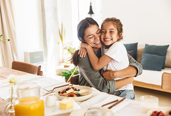 Mom and Daughter Hugging at Kitchen Table