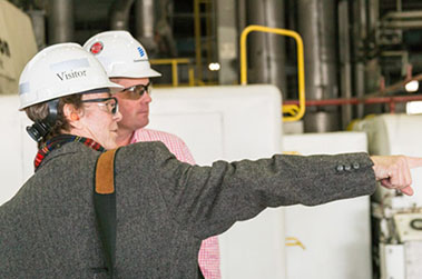 Businessmen in safety goggles and hard hats have a discussion