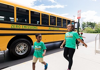 Children walking to the electric school bus