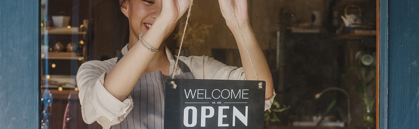 Business Owner Placing Open Sign on Window