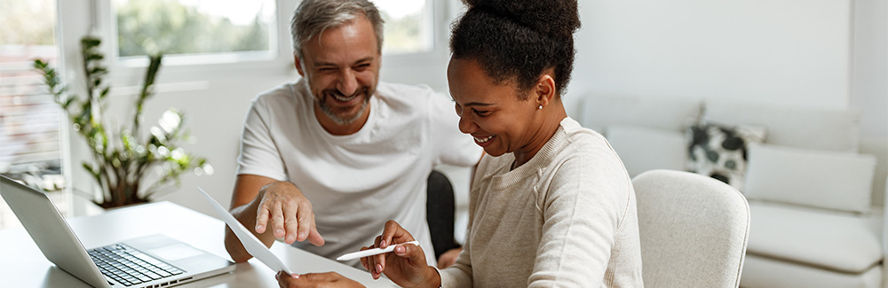 A man and woman smile while reviewing a bill