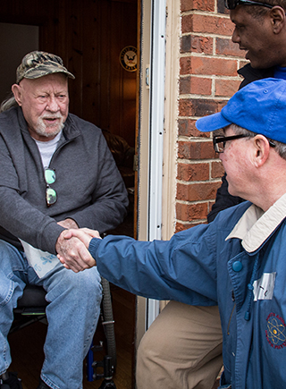 Veteran in wheel chair shaking hands with volunteer