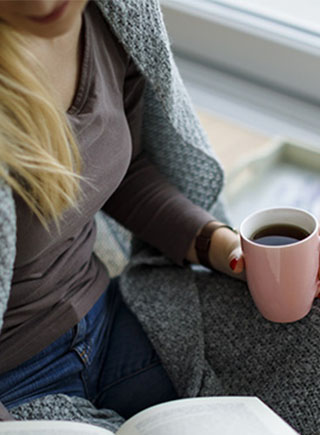 woman wrapped in blanket drinking coffee